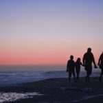 silhouette of 3 men and woman standing on beach during sunset