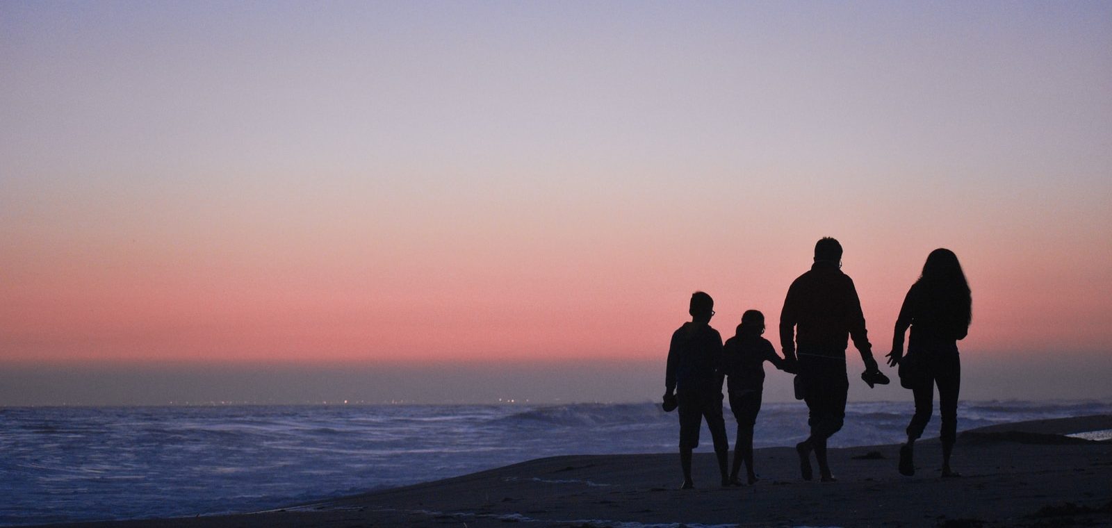 silhouette of 3 men and woman standing on beach during sunset